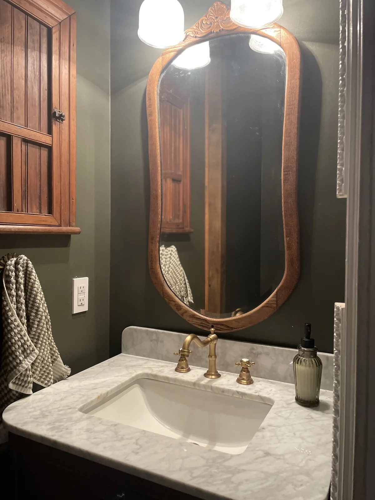 Finished half bath with marble-top vanity, brass fittings and dark walls