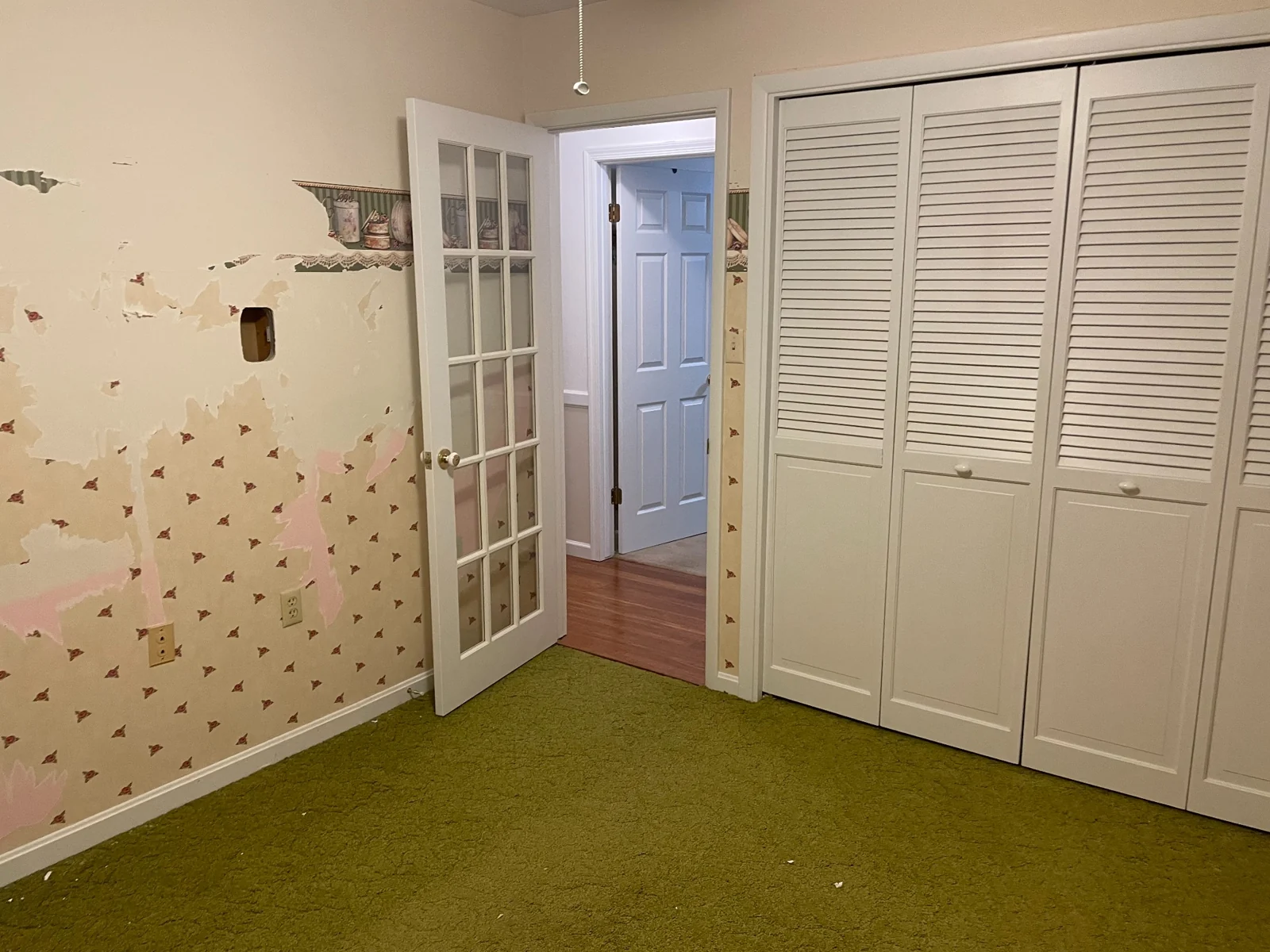 Nursery before transformation with patterned wallpaper and green carpet